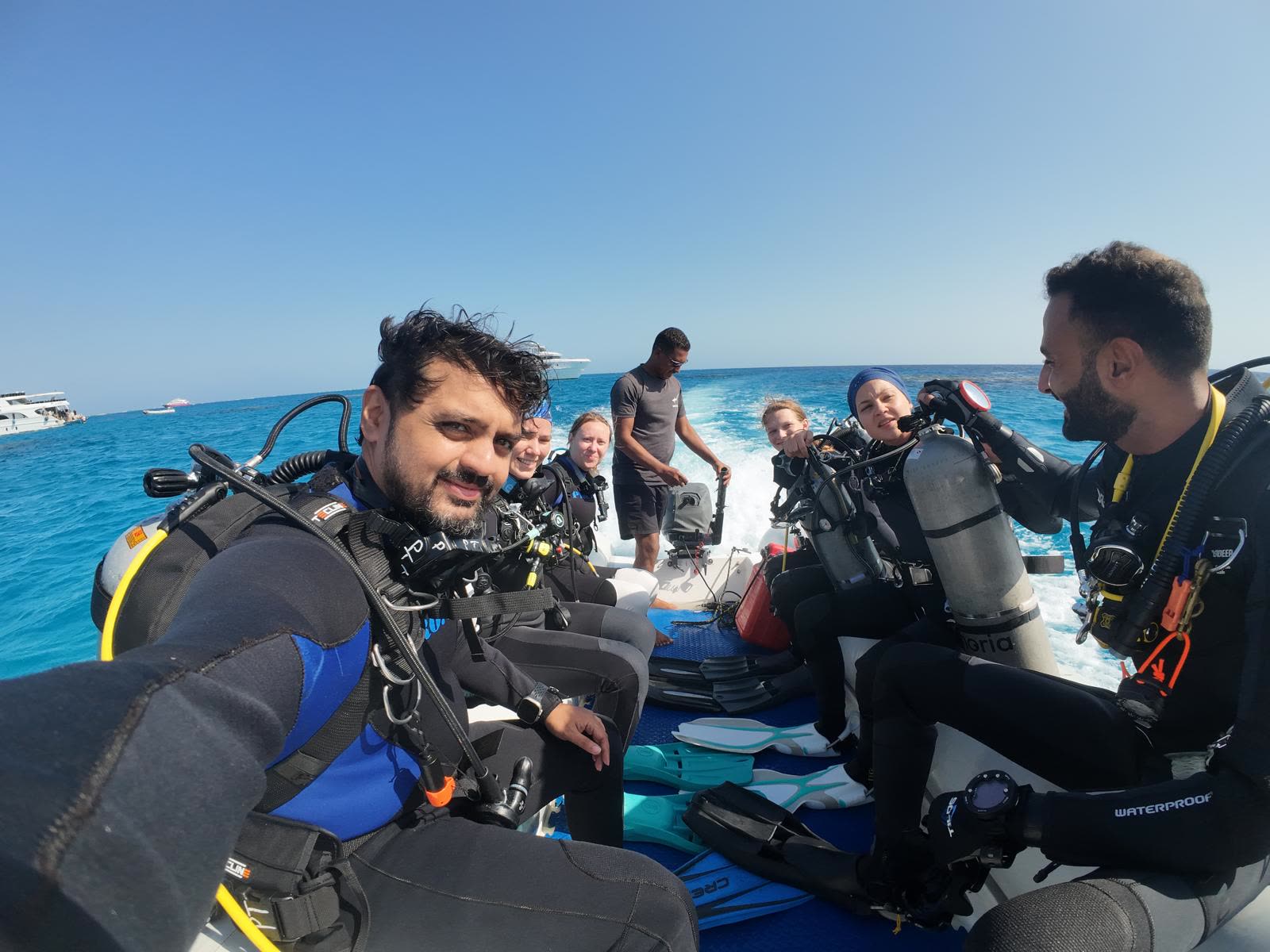 Divers sitting along the benches in full kit on the way out to the site.