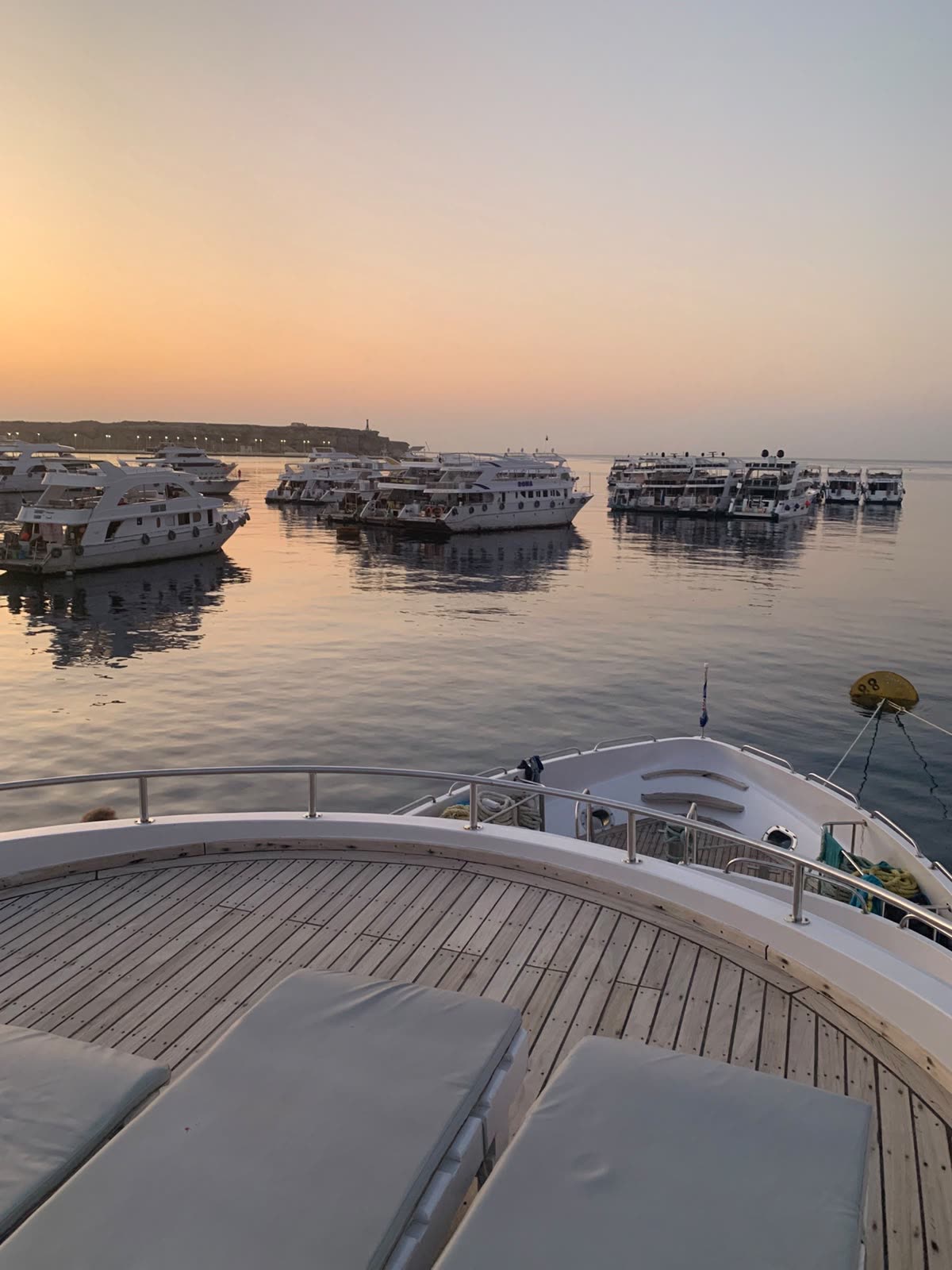 Boats at their moorings in soft morning light, seen from the deck.